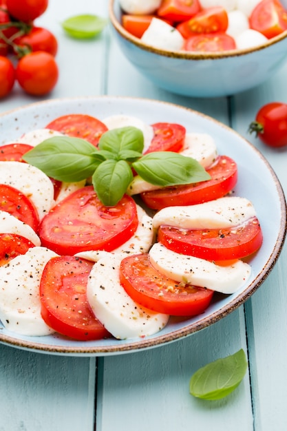 Tomates, fromage mozzarella, basilic et épices sur tableau en ardoise grise. Ingrédients de la salade caprese traditionnelle italienne. Un plat méditerranéen.