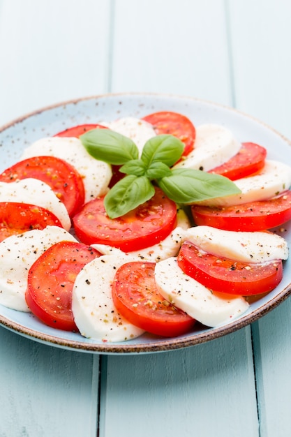 Tomates, fromage mozzarella, basilic et épices sur tableau en ardoise grise. Ingrédients de la salade caprese traditionnelle italienne. Un plat méditerranéen.