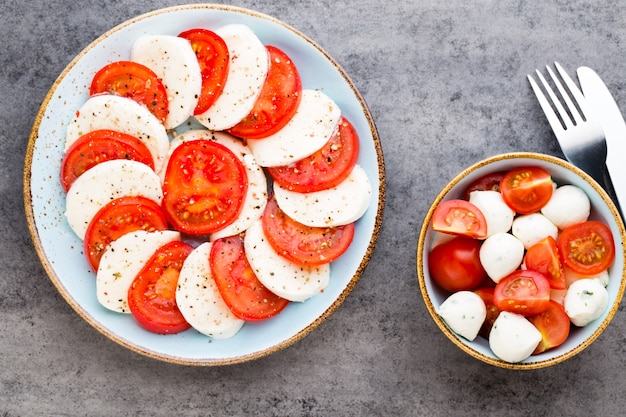 Tomates, fromage mozzarella, basilic et épices sur tableau noir en ardoise grise