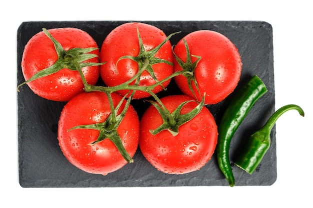 Tomates et gousse de piment sur une planche à découper en ardoise fond blanc isolé