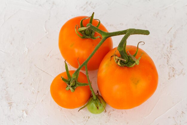 Tomates jaunes mûres de plan rapproché sur le fond texturisé blanc Ingrédients pour la nourriture végétarienne