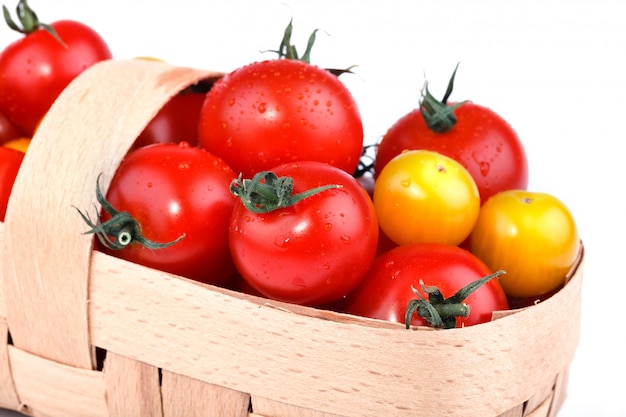 Tomates jaunes et rouges se trouvent dans le panier sur une surface blanche