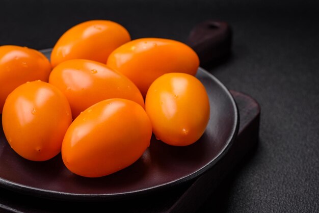 Tomates juteuses fraîches en forme de prune jaune sur un fond de béton à texture noire