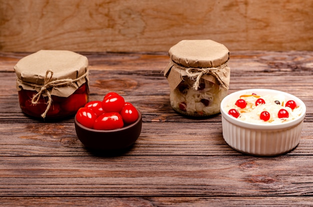 Tomates marinées fermentées maison et choucroute aux canneberges dans des bols sur un fond en bois.