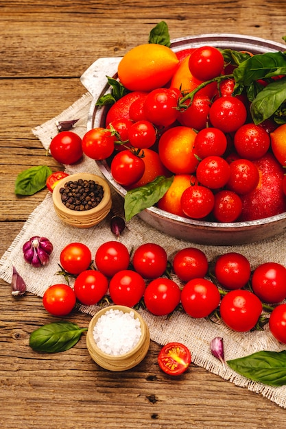 Tomates multicolores mûres assorties. Jeune ail, feuilles de basilic frais, sel, épices