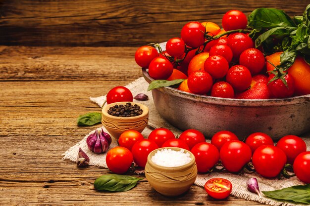 Tomates multicolores mûres assorties. Jeune ail, feuilles de basilic frais, sel, épices