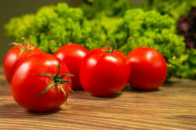 Tomates mûres fraîches sur une table en bois avec une salade verte sur le fond Légumes frais