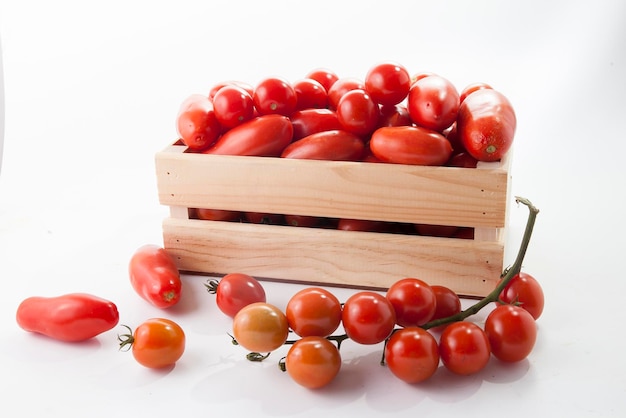 Tomates mûres sur mensonge dans une boîte en bois sur fond blanc