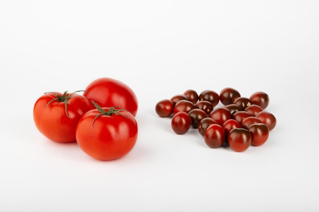 Tomates mûres rouges et petites tomates cerises mûres sur fond blanc