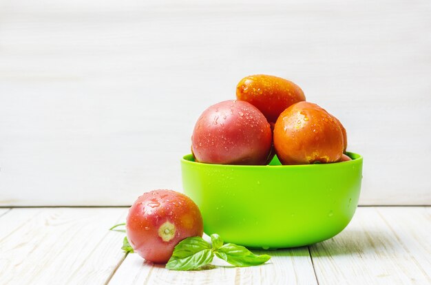 Tomates naturelles mûres et basilic dans un bol vert.