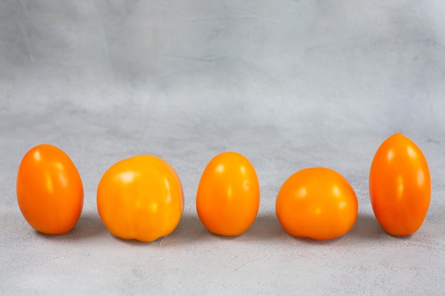 Tomates oranges jaunes fraîches mûres sur fond gris clair