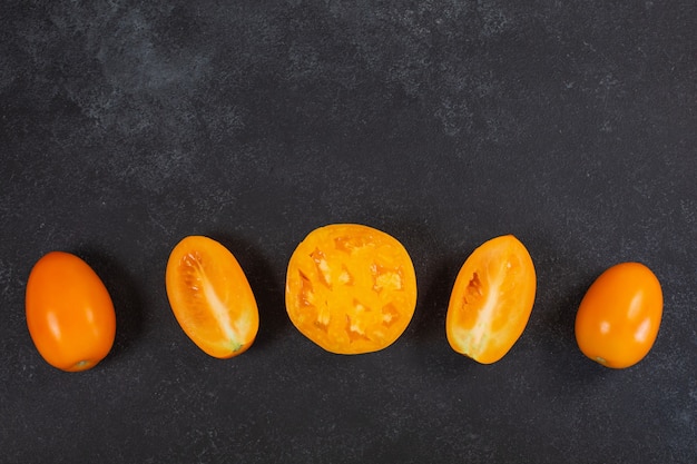 Tomates oranges jaunes fraîches mûres sur fond noir