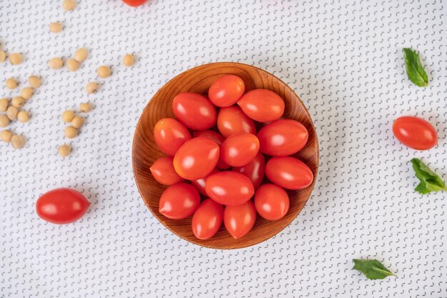 Des tomates placées dans une tasse en bois sur un tissu blanc