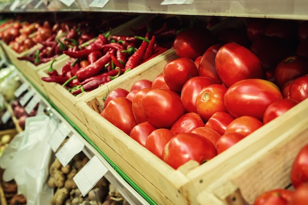 Tomates et poivrons rouges sur une étagère de légumes de supermarché