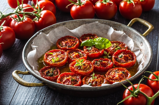 Tomates rôties à l'huile d'olive thym origan et basilic dans une poêle.