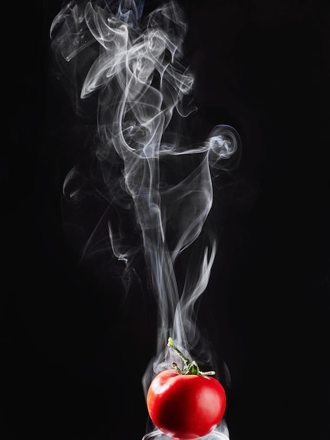 Photo tomates rouges sur fond noir avec de la fumée