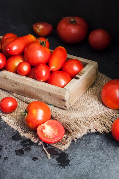 Tomates rouges fraîches dans une boîte en bois sur fond noir.