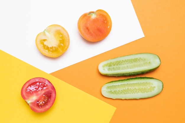 Tomates rouges et jaunes au concombre sur blanc et jaune