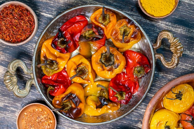 Tomates rouges et jaunes et poivrons au four. Tomates et poivrons dans un plat allant au four sur une table en bois. Un plat végétarien sain et délicieux. Gros plan, vue de dessus