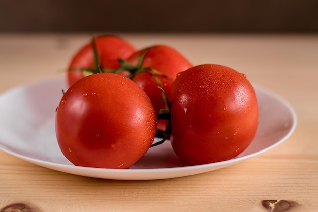 Tomates rouges juteuses fraîches dans une assiette blanche