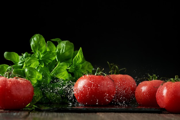 Tomates rouges mûres fraîches sur une planche à découper avec du basilic frais sur un fond en bois
