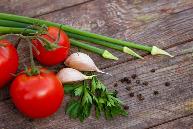 Tomates rouges oignons verts et ail et persil avec pois noirs sur fond de bois gros plan avec...