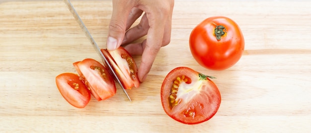 Tomates rouges et tranches sur une planche à découper en bois