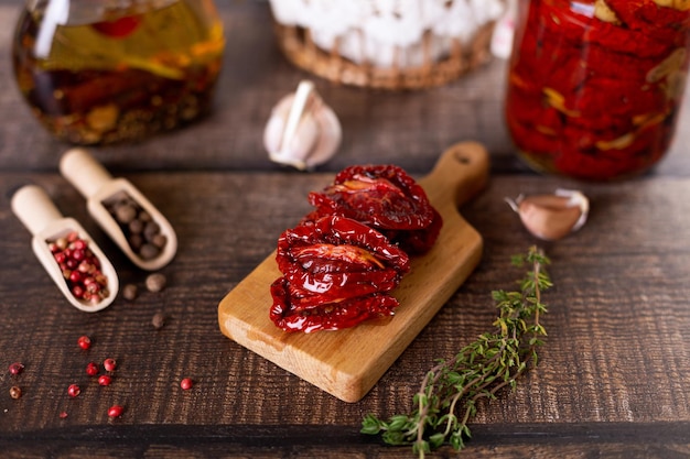 Tomates séchées au soleil dans l'huile d'olive sur une mini planche avec du poivre, de l'ail et du thym dans un style rustique gros plan de mise au point sélective