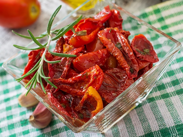 Tomates séchées au soleil avec des herbes et de l'ail dans un bol en bois