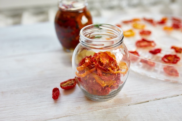 Tomates séchées au soleil maison aux herbes, ail à l'huile d'olive dans un bocal en verre sur fond de bois blanc. Copiez l'espace, gros plan. Imprimer pour la cuisine.