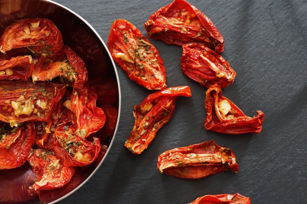 Photo tomates séchées au soleil en petits morceaux se trouvant dans un plat en métal sur fond sombre