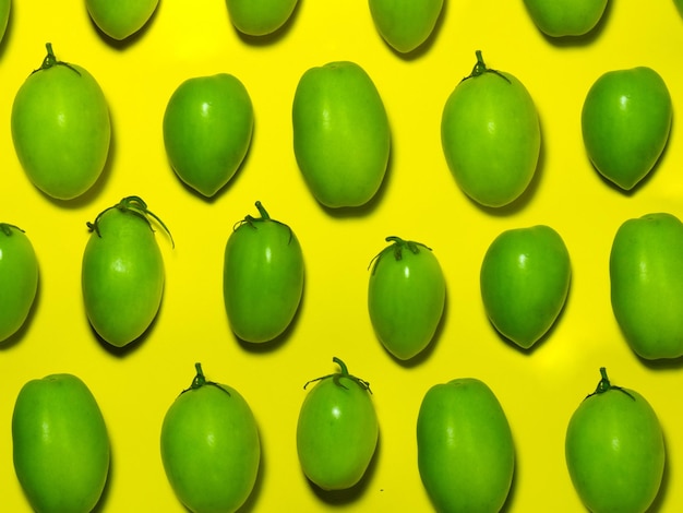 Tomates vertes sur un fond jaune Le concept d'un légume immature Arrière-plan à partir de légumes verts Produit de salage