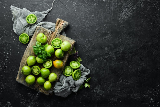 Tomates vertes fraîches sur fond de pierre noire Légumes verts Vue de dessus Espace libre pour votre texte