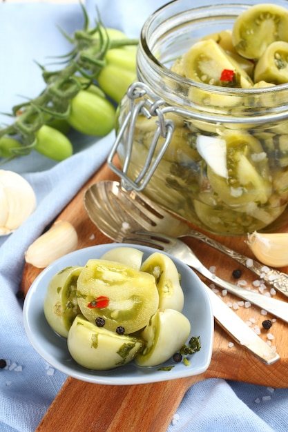 Tomates vertes marinées dans un bol bleu et dans un bocal en verre