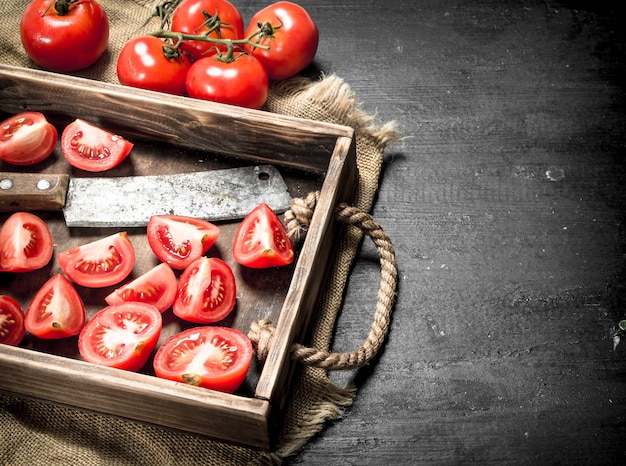 Tomates avec vieille hachette sur le plateau sur tableau noir