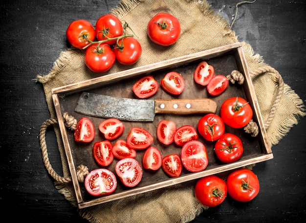 Tomates avec vieille hachette sur le plateau sur tableau noir