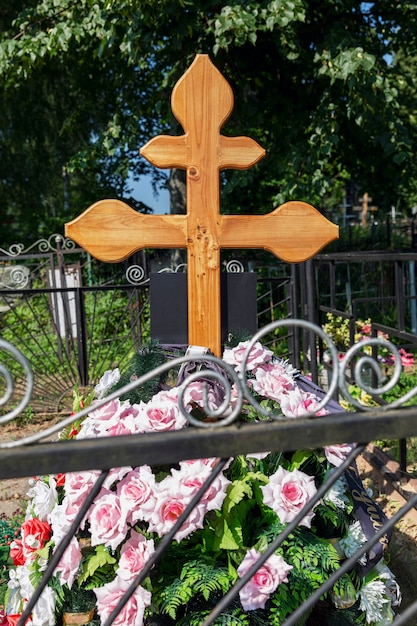 Tombe fraîche avec une croix dans le cimetière. Chagrin et mémoire. Verticale.