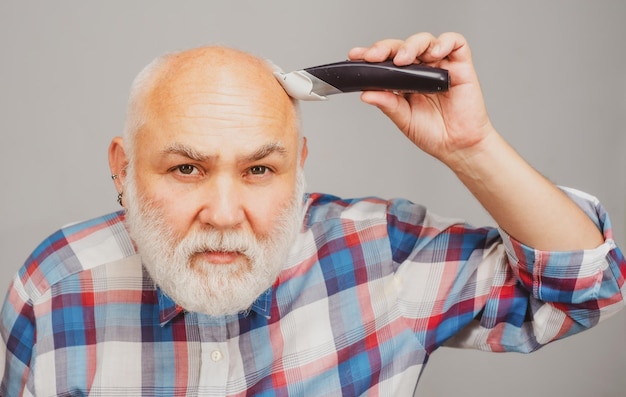 Tondeuse à cheveux homme chauve calvitie mature et concept de perte de cheveux homme gris d'âge moyen