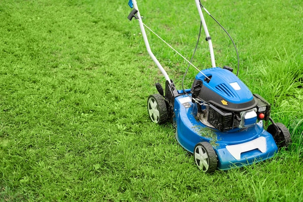 Tondeuse à gazon coupant de l'herbe De petites coupures d'herbe s'envolent de la tondeuse à gazon Des tontes de gazon sont vomies par une tondeuse poussée par un paysagiste