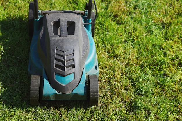 Tondeuse à gazon électrique coupe herbe verte. La différence entre les parties traitées et envahies du champ.