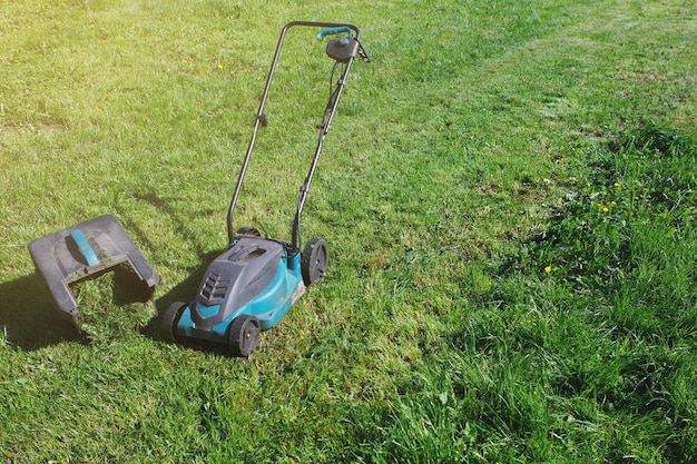 Tondeuse à gazon électrique coupe herbe verte. La différence entre les parties traitées et envahies du champ.