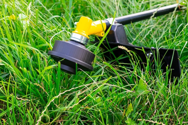 Tondeuse pour tondre l'herbe dans le jardin parmi l'herbe épaisse