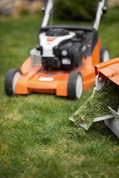 Photo tondre l'herbe verte lors d'une journée de printemps ensoleillée avec une nouvelle tondeuse à gazon