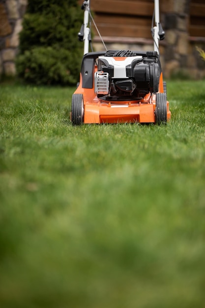 Tondre l'herbe verte lors d'une journée de printemps ensoleillée avec une nouvelle tondeuse à gazon