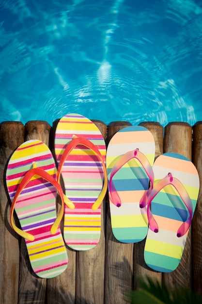Tongs sur bois contre l'eau bleue concept de vacances d'été