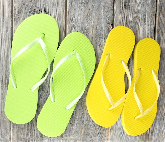 Des tongs de couleur sur une planche de bois isolée sur du blanc