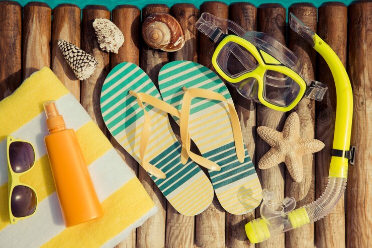 Photo tongs et crème solaire sur bois contre l'eau bleue concept de vacances d'été et de soins de santé