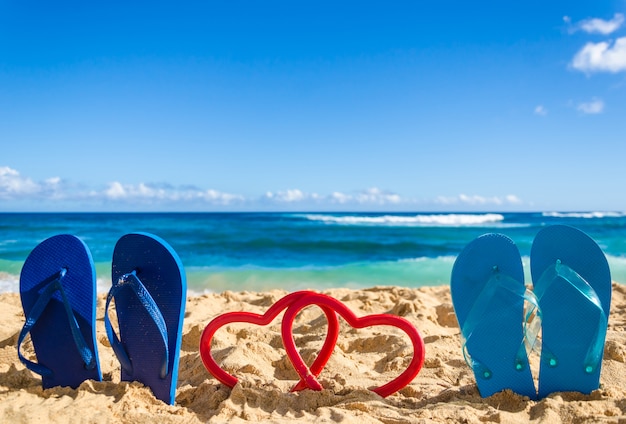 Tongs avec des formes de coeur sur la plage de sable