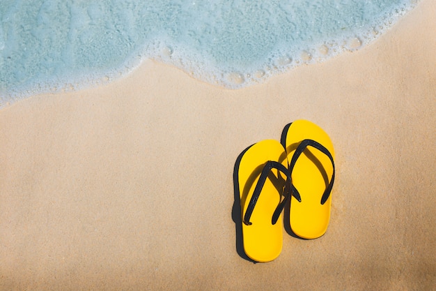 Tongs jaunes sur la plage de sable fin.