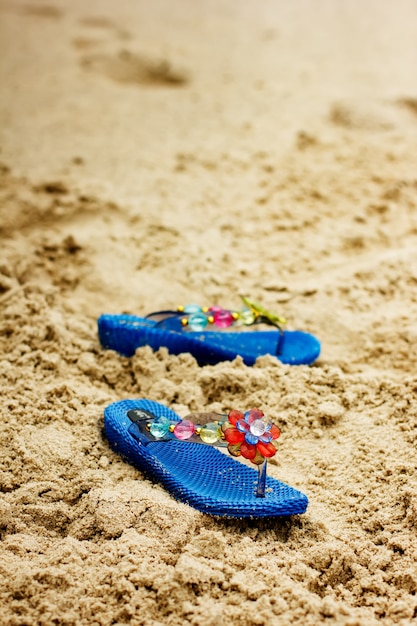 Tongs de plage sur la côte de sable tropicale